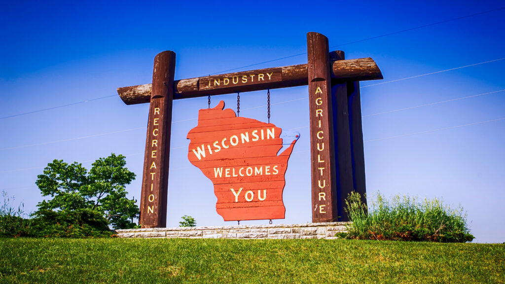 Wisconsin welcomes you sign with words 'recreation' 'industry' and 'agriculture' carved into the frame.