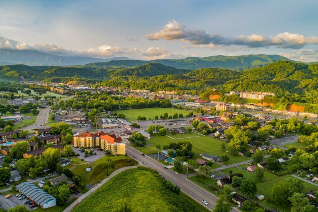 An aerial view of Pigeon Forge, TN, and the mountains surrounding it as the sun sets over the hills.