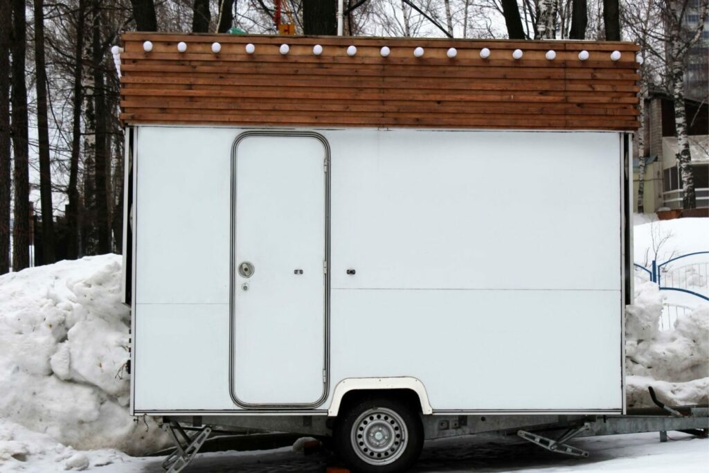 A white cargo trailer with a wood design and lights along the roof has been converted to a mobile business.