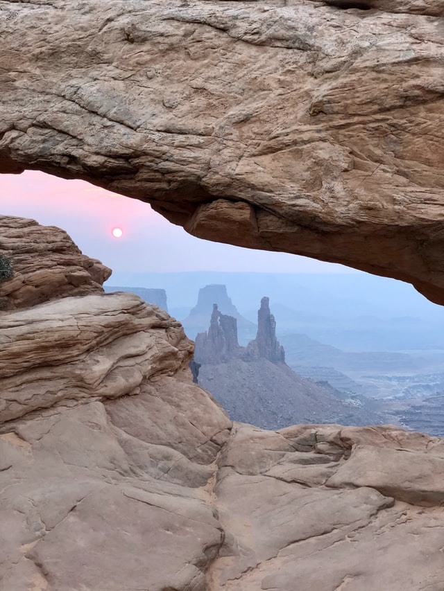 A hazy pastel sunrise over rock formations in Canyonlands Nation Park, Utah