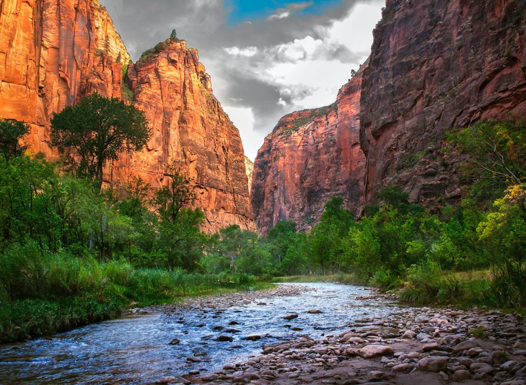 A river flowing through a a canyon with tall, towering sides in Zion Nation Park, Utah