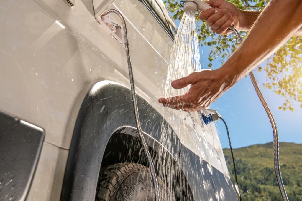 A person uses an outdoor RV shower with hot water to get cleaned up.