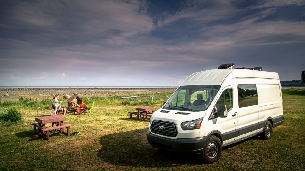 A family enjoys a picnic in a field beside their RV rental