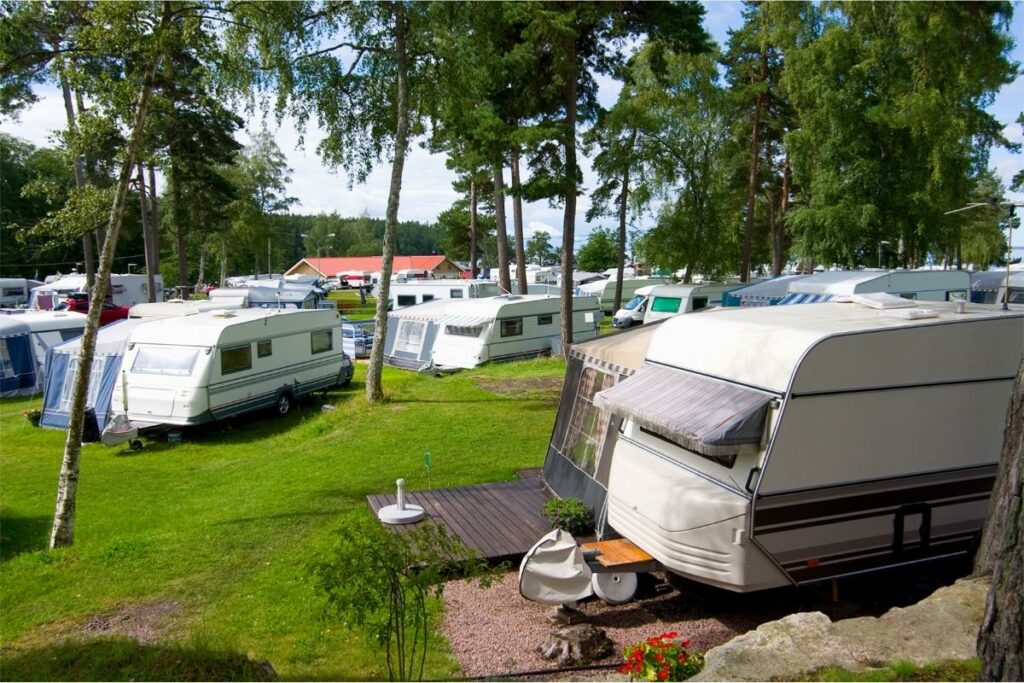 A crowded campground is packed in tightly with many travel trailers and motorhomes/