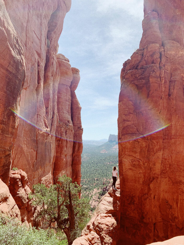 A hiker along a cliff edge at Cathedral Rock, well known as a vortex in Sedona, AZ.