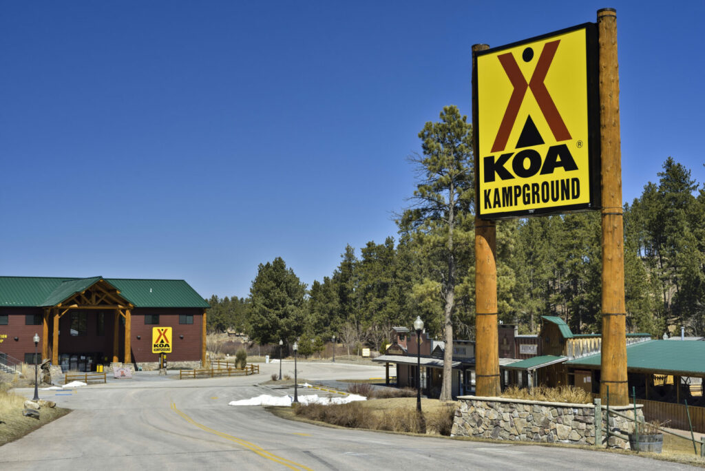 A bright yellow KOA campground sign in front of a wooden building 