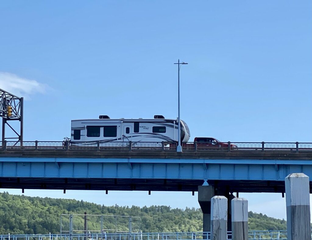 A truck towing a fifth wheel crossing over a bridge 