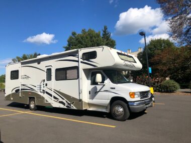 An RV is parked in a parking lot where they are allowed to overnight camp for free.