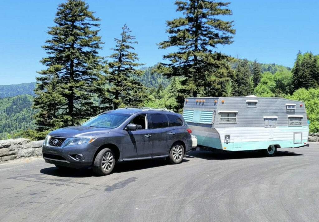 A Subaru towing a vintage travel trailer that is available as an RV Rental in Michigan
