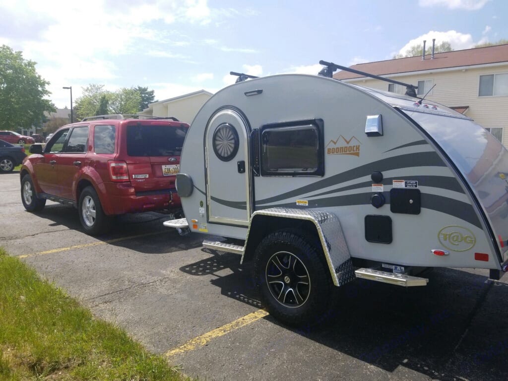 A small teardrop camper attached to a 4Runner SUV in a parking lot