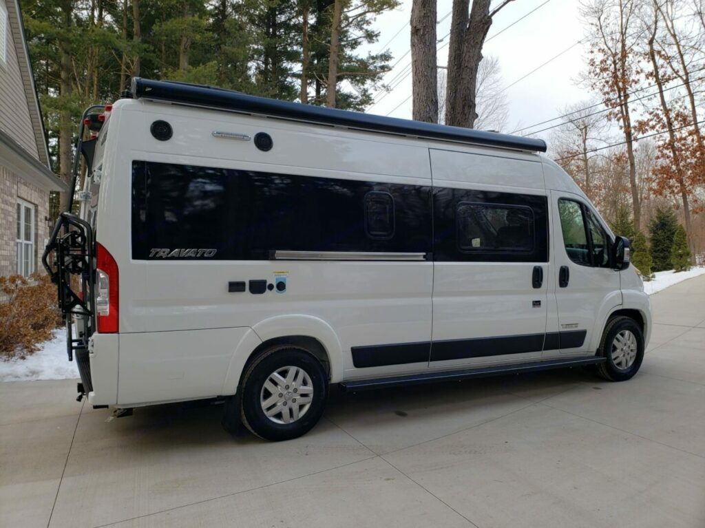 A Winnebago Travato Class B parked in a driveway with snow 