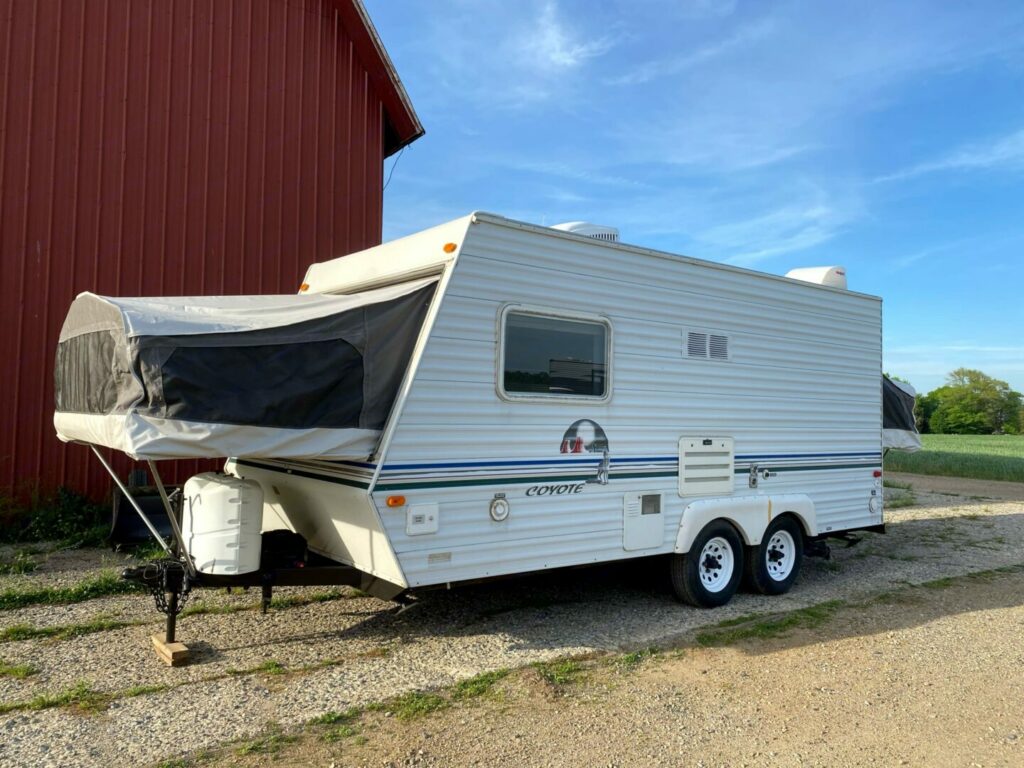 A hybrid camper outside of a barn with the pop out extended