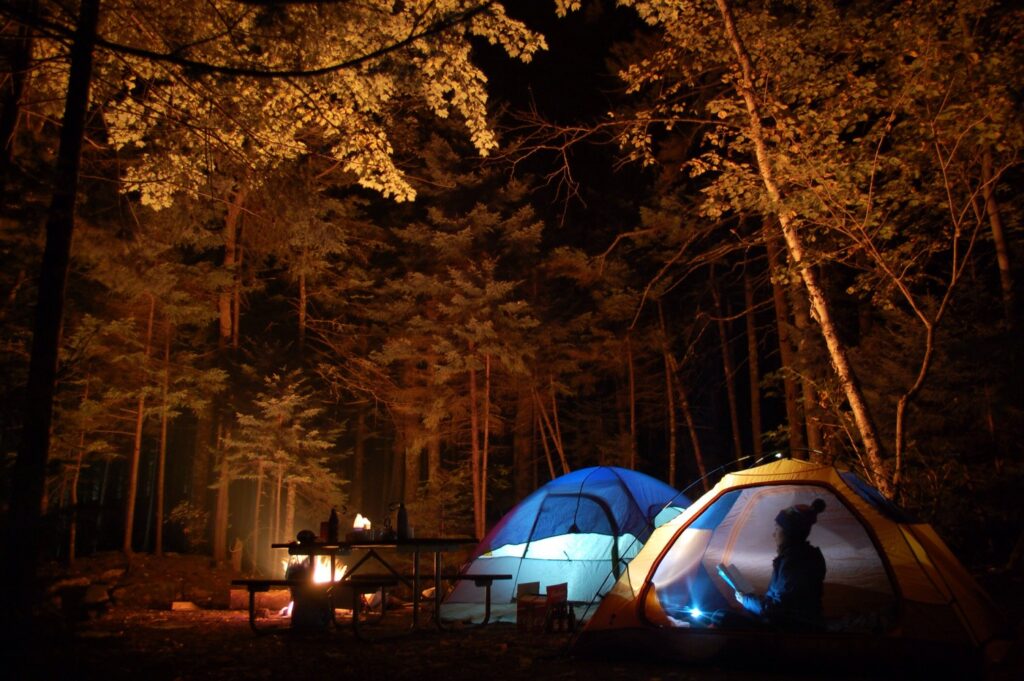 Tents set up in a campsite at night with a campfire in the background