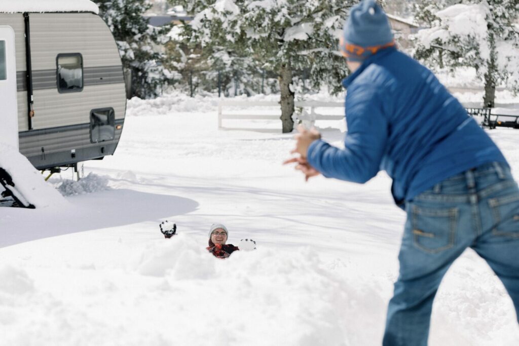 Two male teenagers playing in the snow in front of their RV