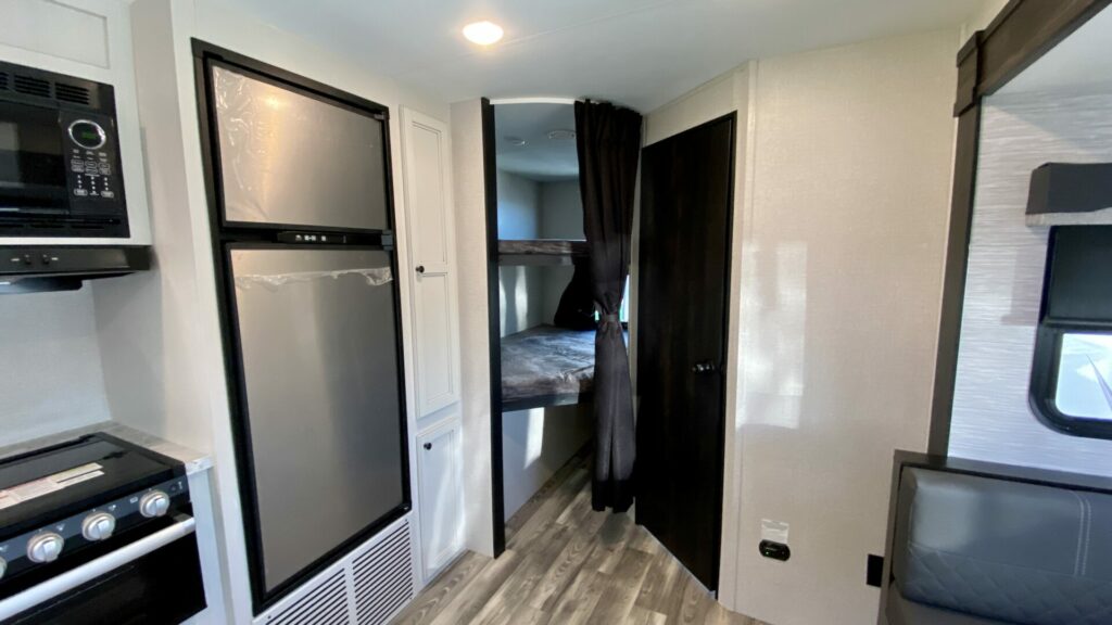 An RV with bunkbeds in the back behind the kitchen