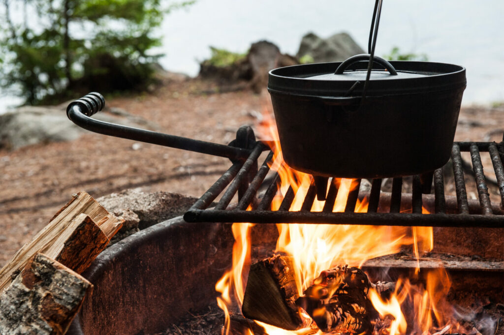 Dutch oven cooking over an open flame on a campfire grill grate