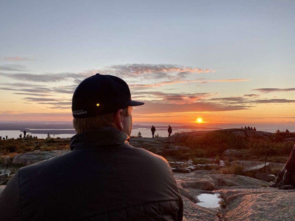 A man looking at the sunrise while camping in Acadia national park 