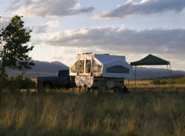 A small pop-up camper sitting in a meadow before the owner puts hard sides on their pop-up camper.