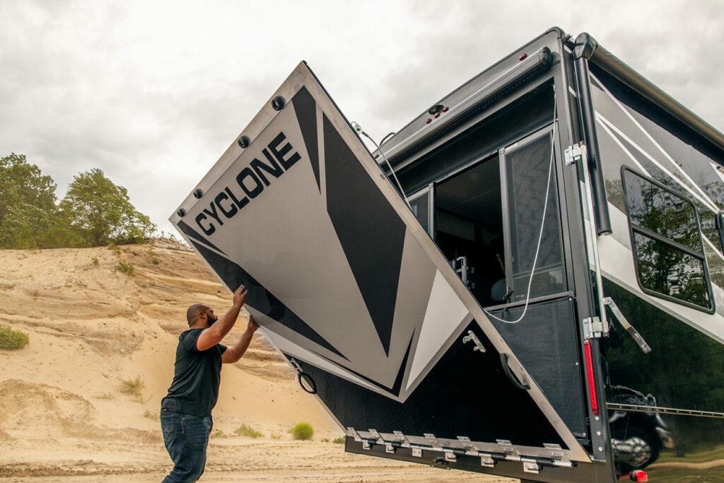 A man in the desert opening the back of a Cyclone Heartland RV toy hauler