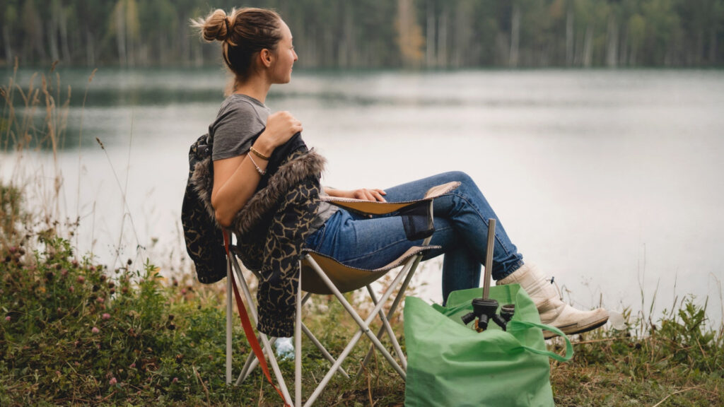 Woman sitting by the lake in her oversized camping chair.