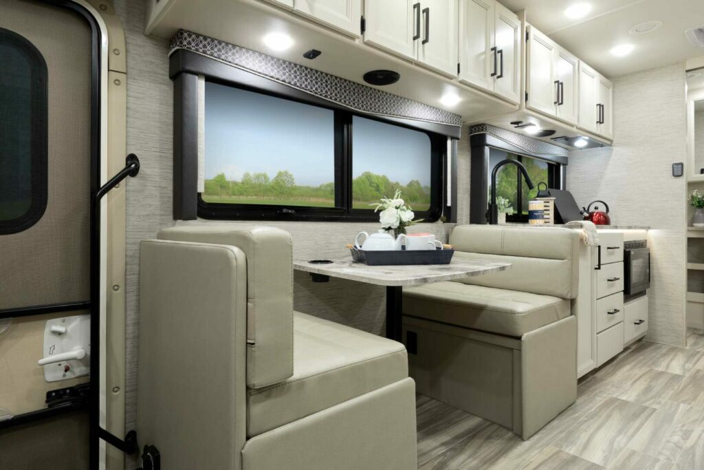 Interior picture of a tan and white RV kitchen owned by Thor Industries