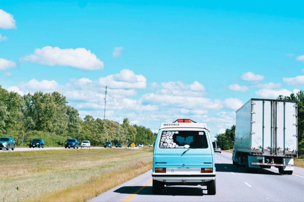 A blue camper van driving down the highway. Highway hypnosis can be dangerous, especially for RVers who live on the road so it is important to take breaks.