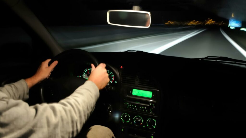 A man at risk for highway hypnosis as he's driving at night with no other cars on the road