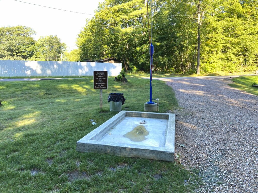 A cement RV dump station with water sitting in a puddle