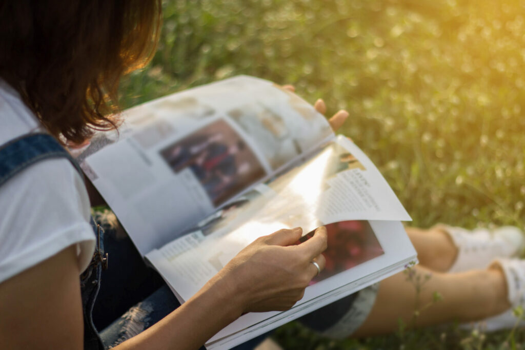 Woman reading RV magazines sitting outside in the sun 