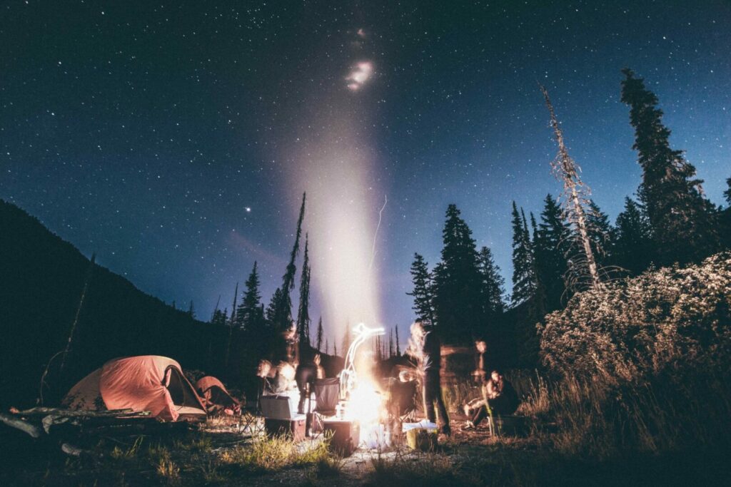 A group of people around a campfire that changing colors at night 