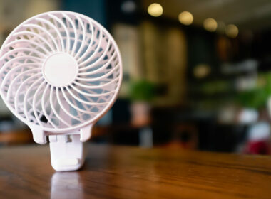 Close up of a portable battery operated fan, folded on a wooden table.