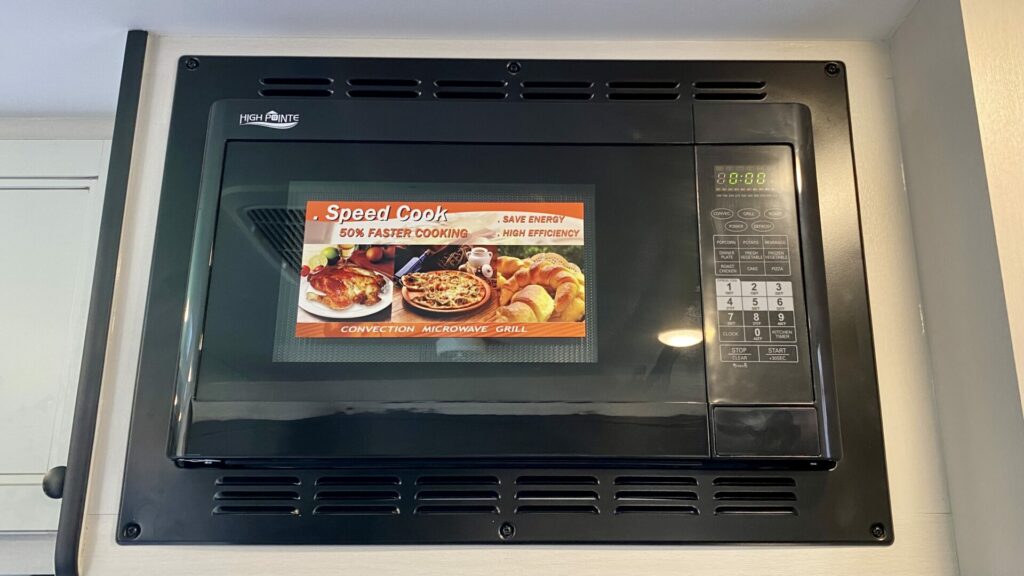A black RV microwave mounted above the stove