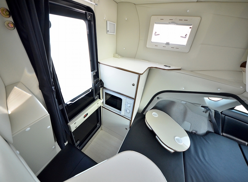 Interior picture of the Prius Camper showing the bed, microwave, and entry door