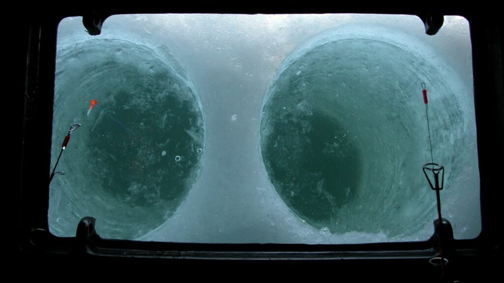 Two ice fishing holes drilled below a hatch in the trailer