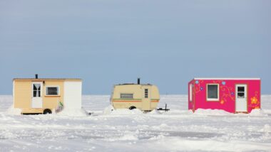 Three ice fishing trailers sitting on a frozen lake