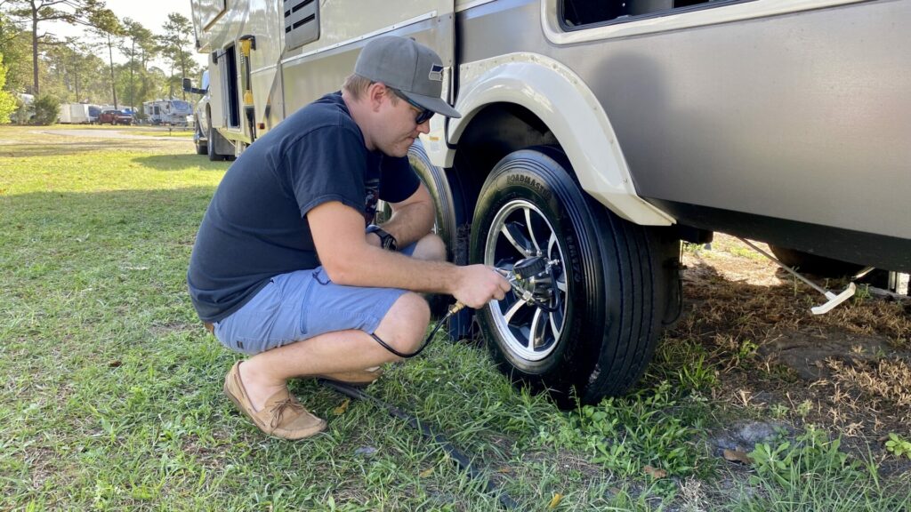 A man using an air compressor to properly inflate his fifth wheel tires