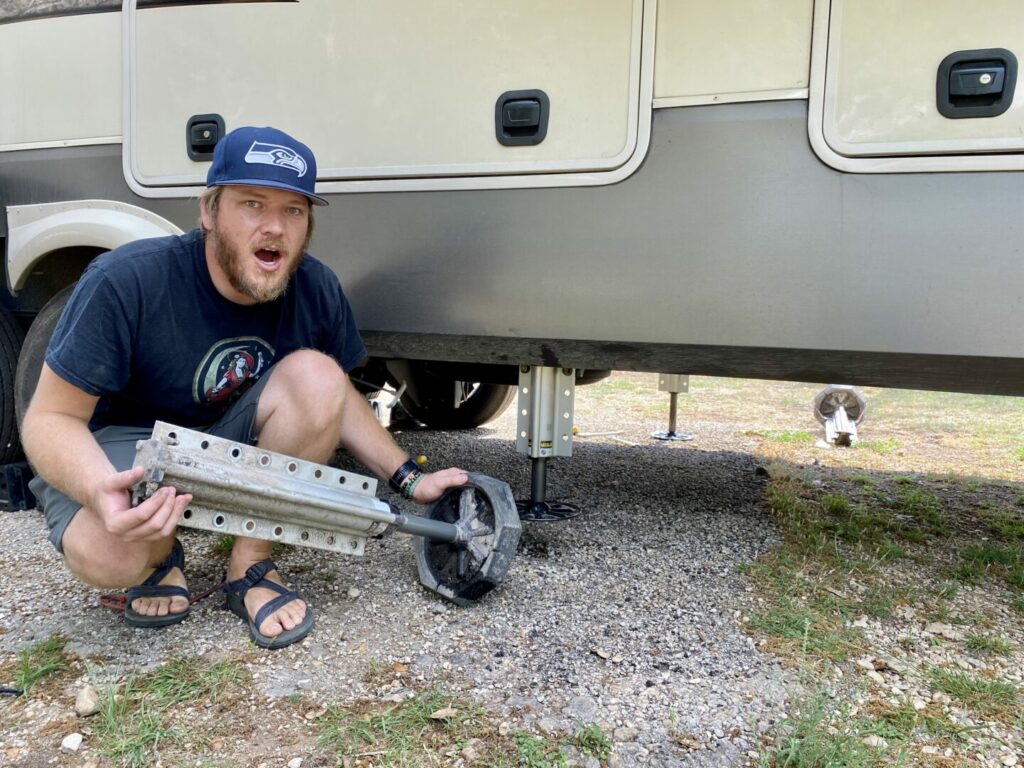 A man holding his RV landing jack with a shocked look on his face