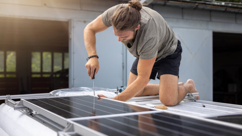 Man working on his RV upgrades by adding solar panels.