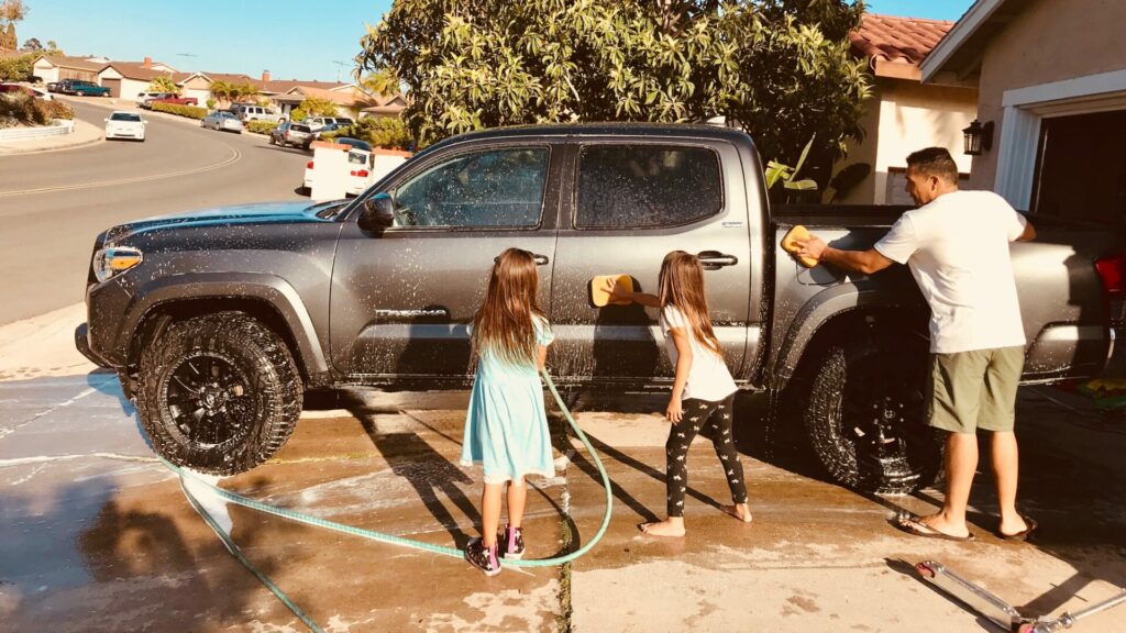 Dad cleaning his gas truck with his daughters after deciding on a diesel vs gas truck.