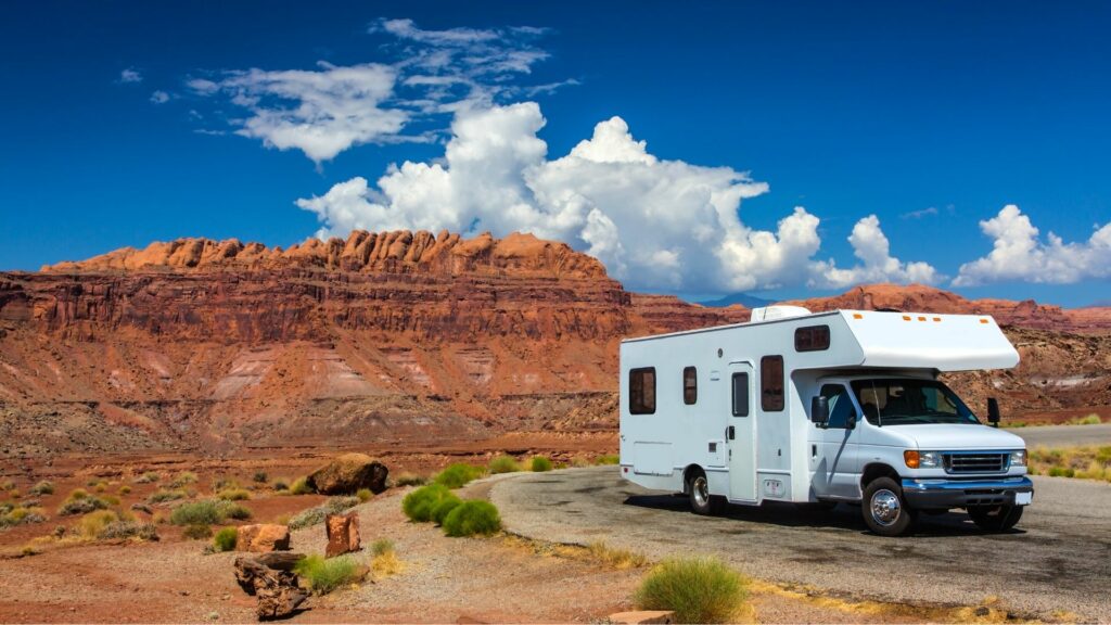 An RV parked on the side of a road with red rocks of Moab Utah in the background