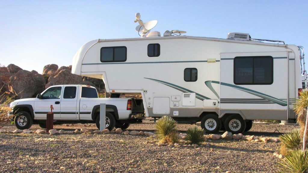 A small fifth wheel camper parked in a desert campsite