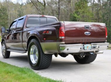 Red dually truck in a driveway with rear tires converted to super singles