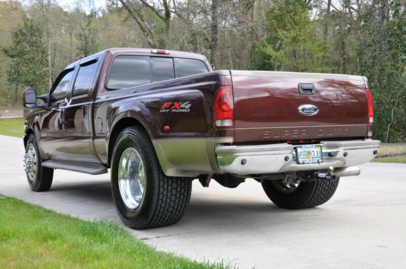 Red dually truck in a driveway with rear tires converted to super singles