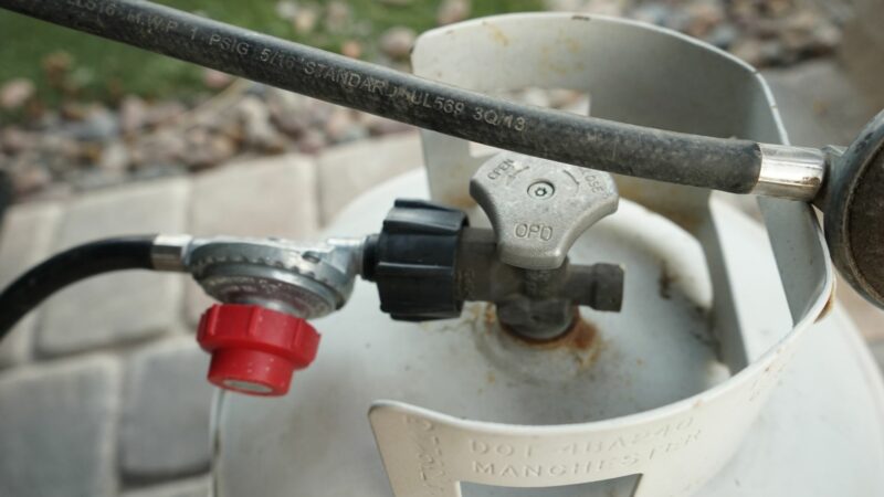 Two propance hoses connected to RV propane tanks with a red regulator on one