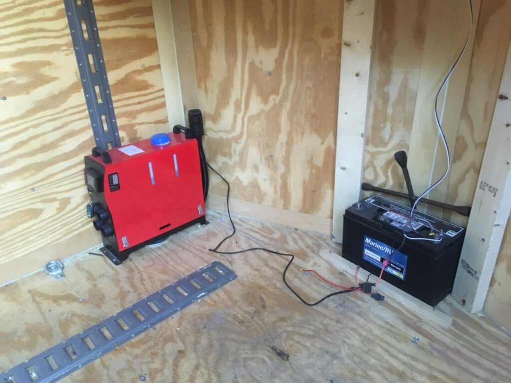 A red 12V All-in-One Air Diesel Heater sitting in the corner of an unfinished building 