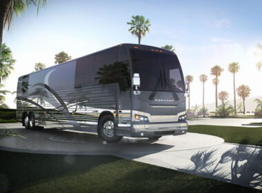 A Prevost RV outside by palm trees.