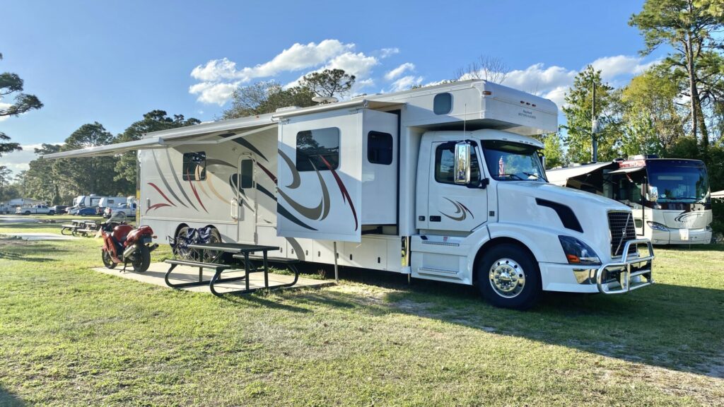 A Super C RV set up in a campground on a sunny day 