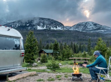 A camper warming his hands at the campfire at a Colorado Campground