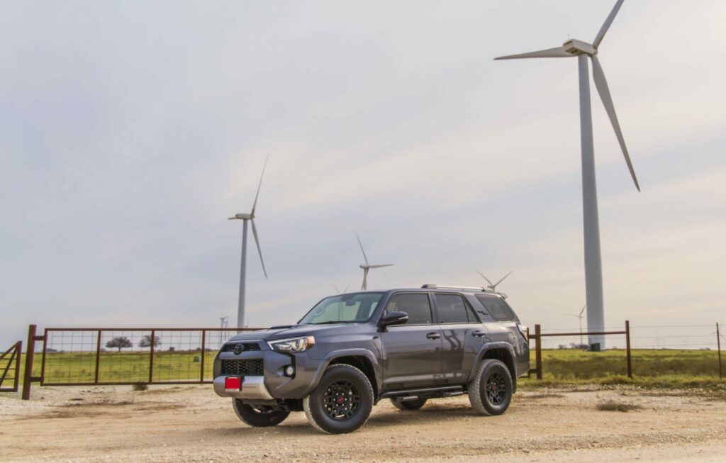 A grey Toyota 4Runner camping next to a wind farm.