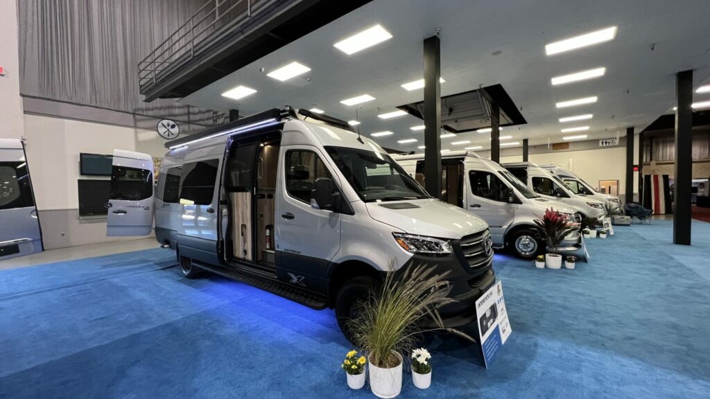 Line of Class B Airstream sprinter vans lined up inside at an RV show